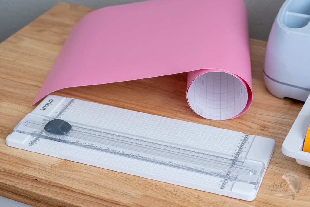 13 inch portable trimmer from Cricut on table with pink vinyl