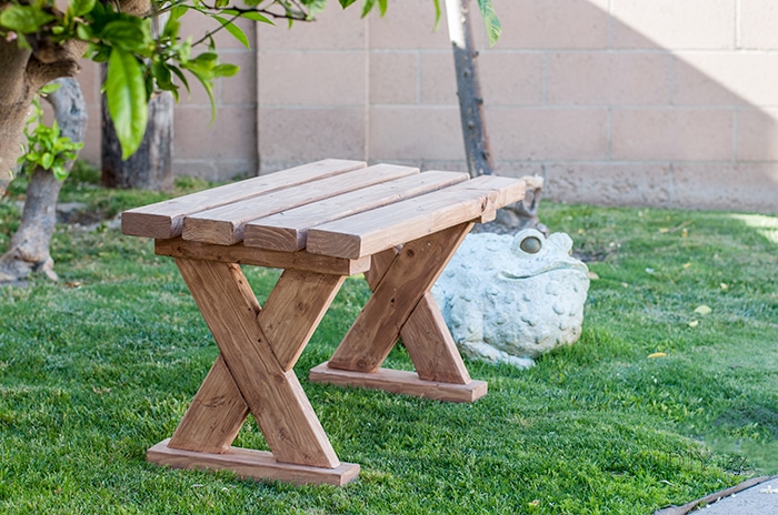 DIY 2x4 x-leg bench outdoors on the grass.