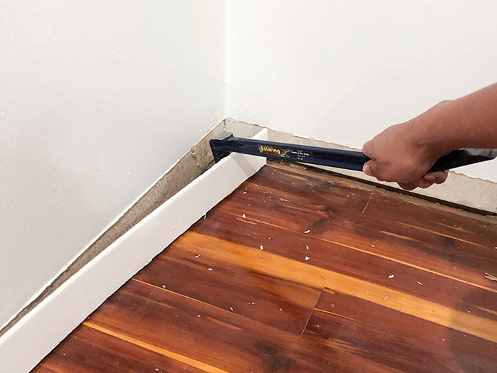 Removing old baseboard to make space for the DIY closet organizer