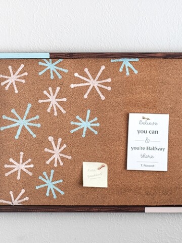 Make a gorgeous DIY cork bulletin board with a roll of cork and scrap wood with this full tutorial with pictures. This easy stenciled cork board adds fun, color, and function to any room!