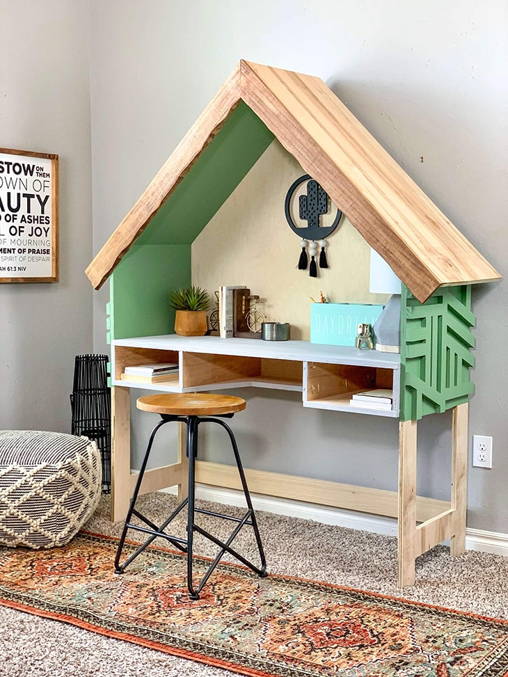House shaped desk with green accents and two open drawers 