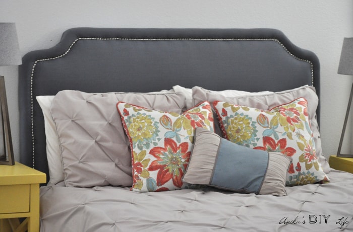 DIY upholstered headboard with nailhead trim and colorful pillows