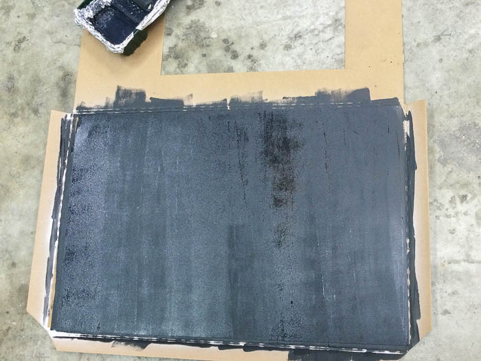 Painting galvanized metal sheet with chalkboard paint using a roler to make a DIY magnetic chalkboard