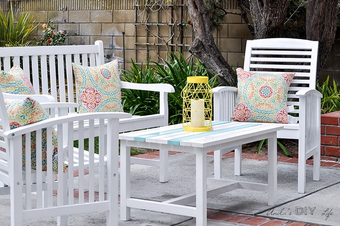 DIY outdoor coffe table in patio with white patio chairs and yellow lantern