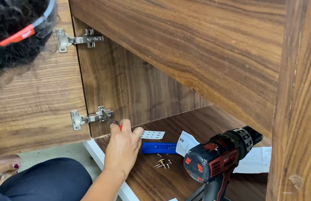 Woman attaching a door to the cabinet