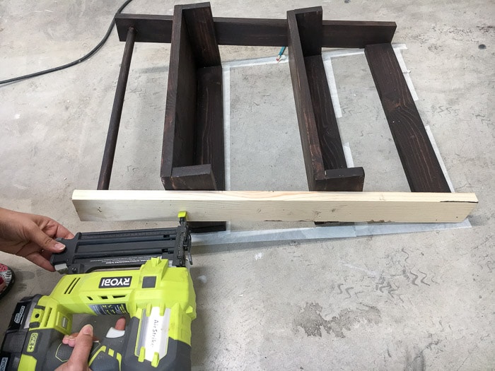 Attaching the side of the floating ladder shelf using glue and finish nails.