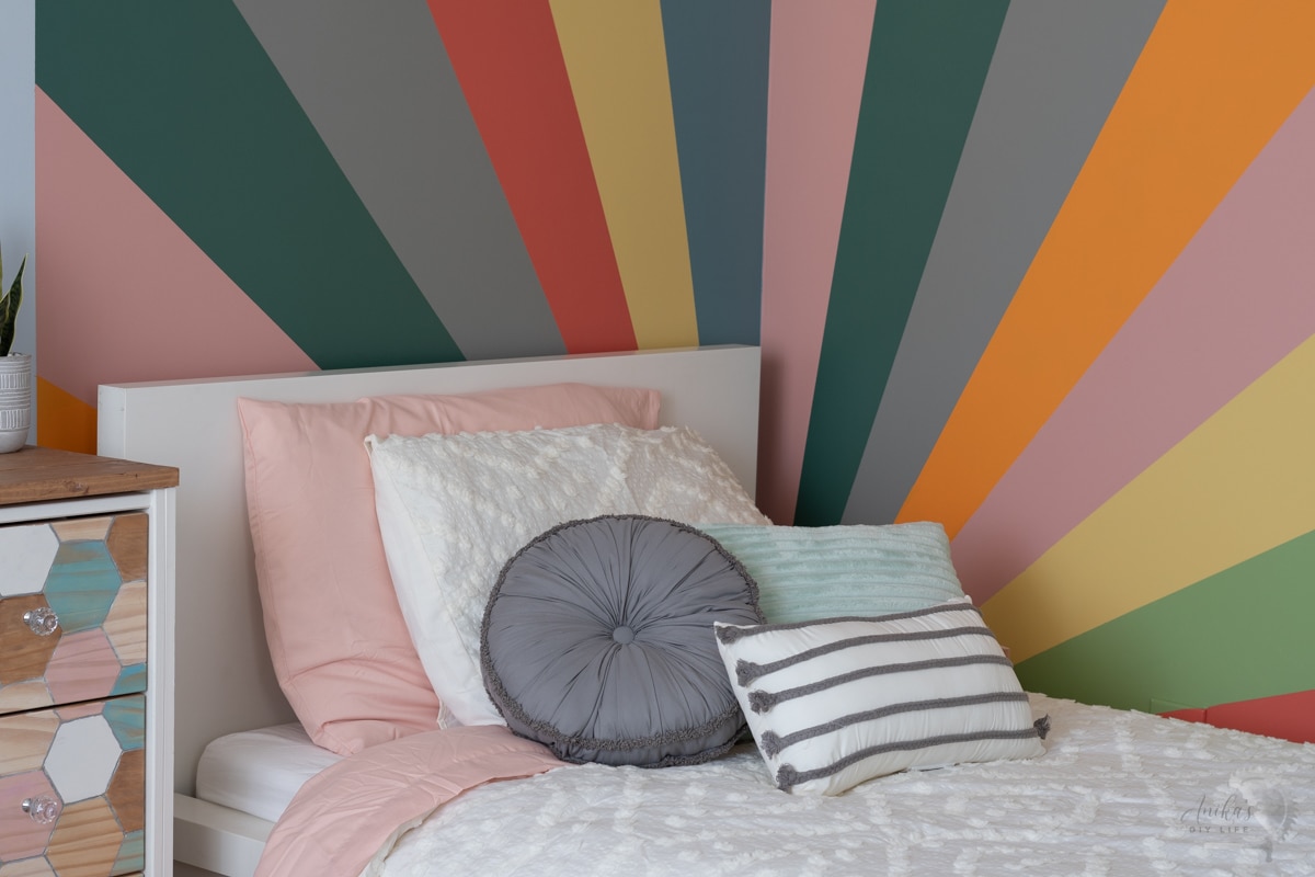 close up of sunburst wall with bed in front of it.