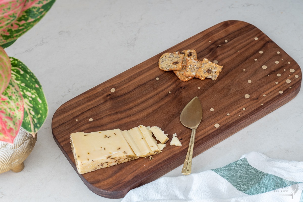 DIY walnut cutting board with brass inlay with cheese and crackers