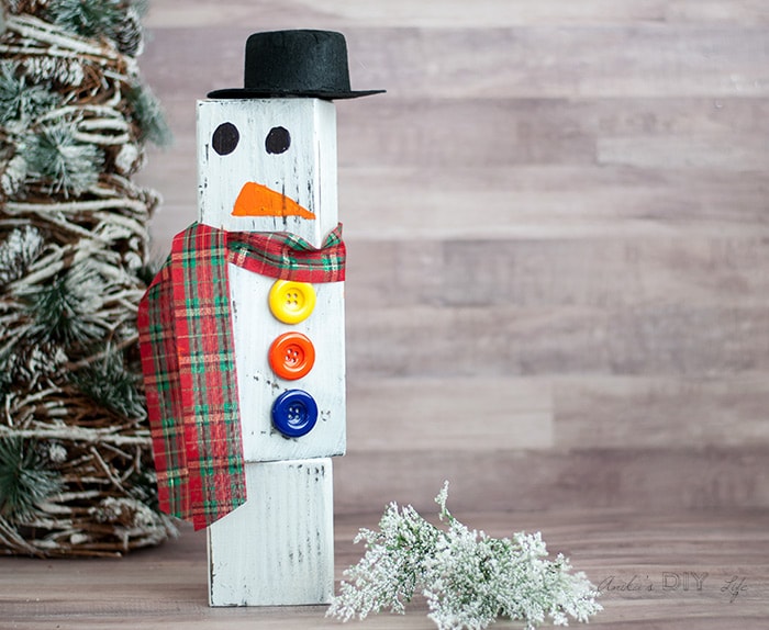 DIY Wood block snowman in front of Christmas tree and shrubs