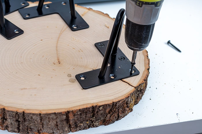 attaching hairpin legs to a wood slice to make a DIY wood slice tray