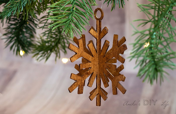 DIY wooden snowflake ornament hanging between branches.
