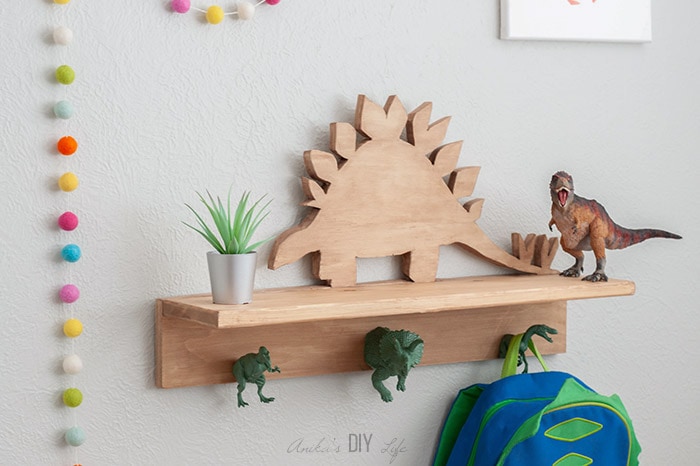 DIY Dinosaur shelf with dinosaur hooks on the wall with backpack hanging