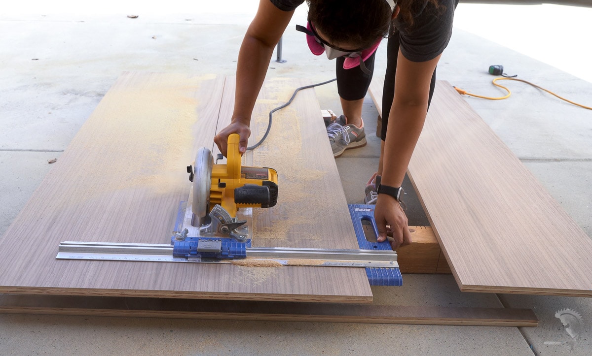 woman cutting plywood using a circular saw on the floor