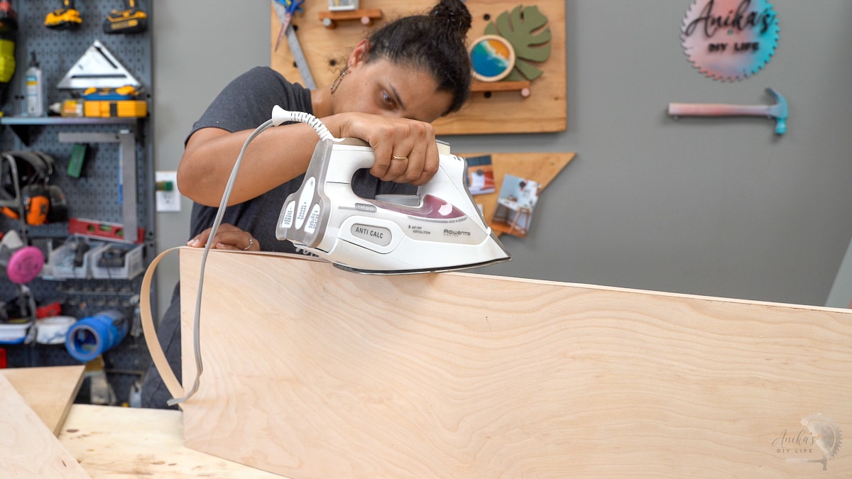 Woman applying edge banding to the plywood shelves