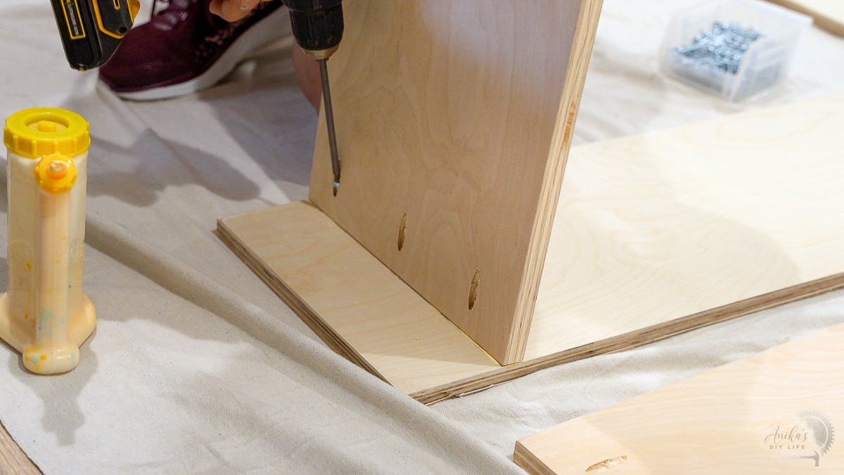 woman attaching shelves to the plywood side for closet organizer