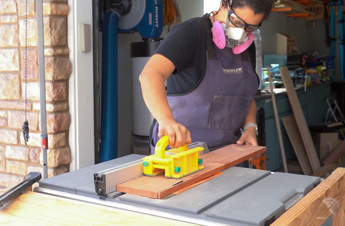 woman trimming off ends of the board on table saw
