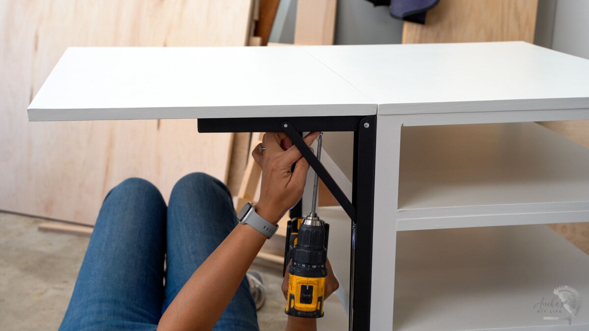 woman attaching the folding shelf bracket to the folding table top.