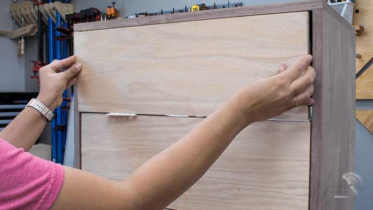 Woman installing plywood drawer fronts on a simple DIY dresser