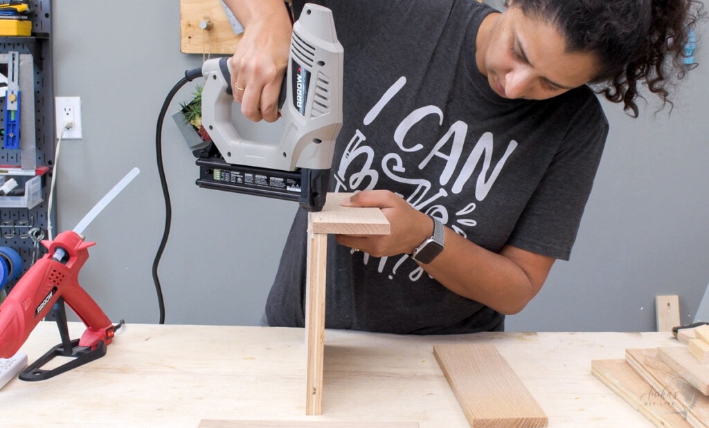 Woman using a nail gun to attach the boards for the multiple device charging station