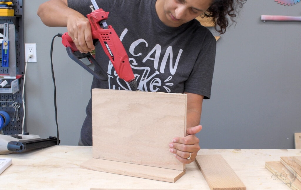 Woman Using hot glue to hold boards in place
