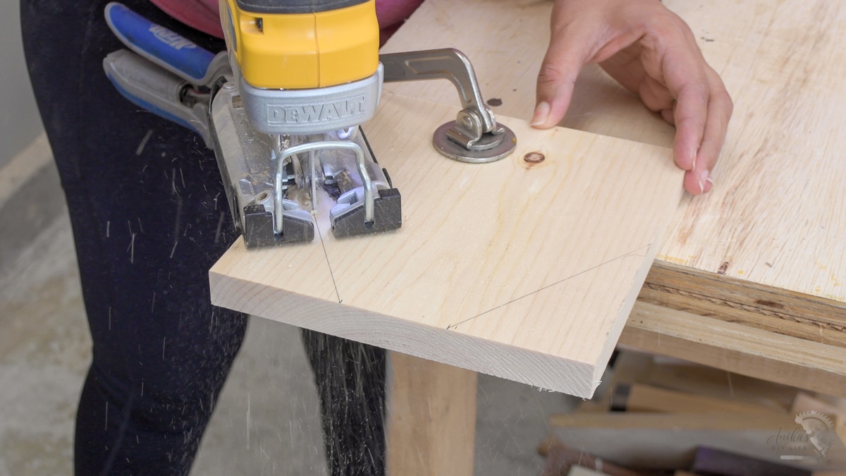 woman cutting board using a jigsaw to make ends of the diy tool box