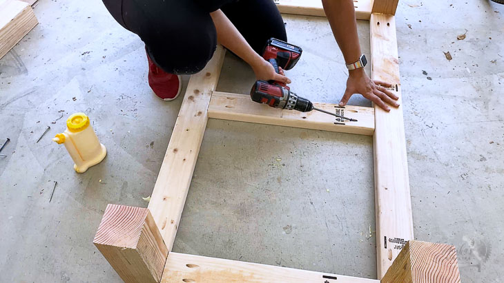 woman building the base of the self-watering planter on a garage floor