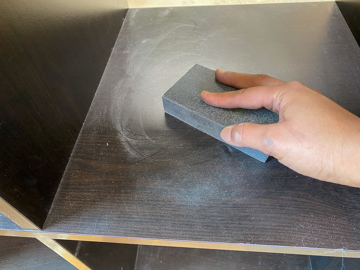 Lightly sanding the Laminate with a sanding sponge to prep it for painting.