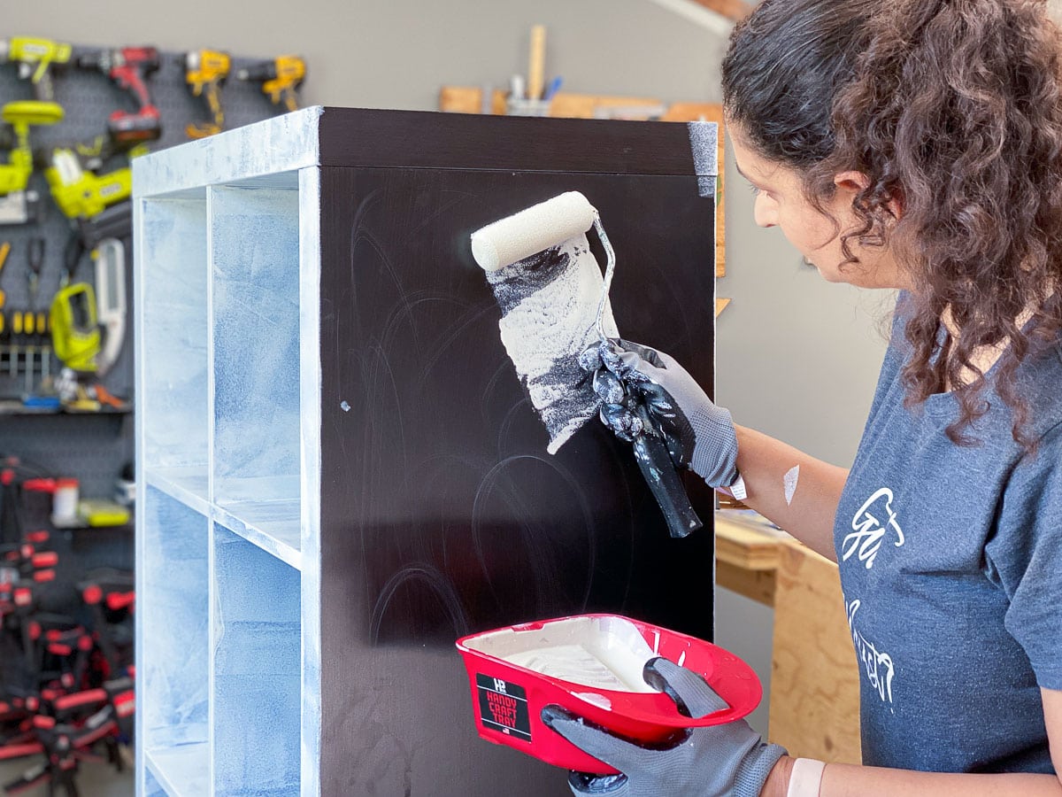 Woman applying shellac based primer on laminate Ikea bookshelf