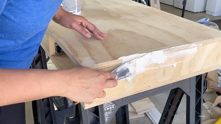 applying joint compound to the plywood to prepare it for painting