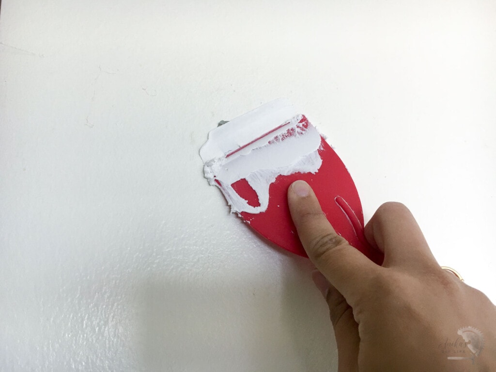 filling nail holes on wall to prepare to paint