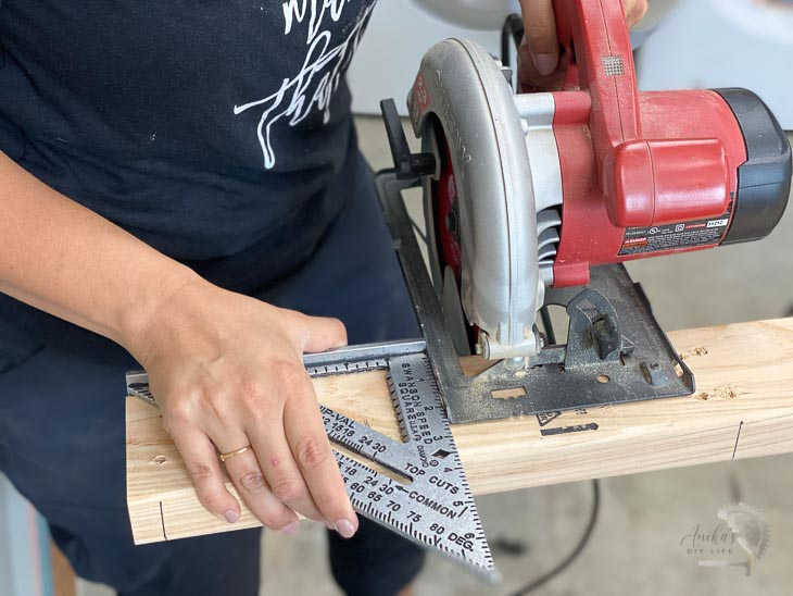 Woman cutting a board with a circular saw using a speed square as a guide.