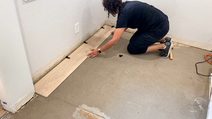 Woman installing the first row of vinyl plank flooring