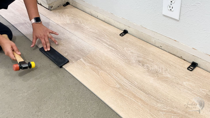 Woman tapping in the second plank of vinyl plank flooring