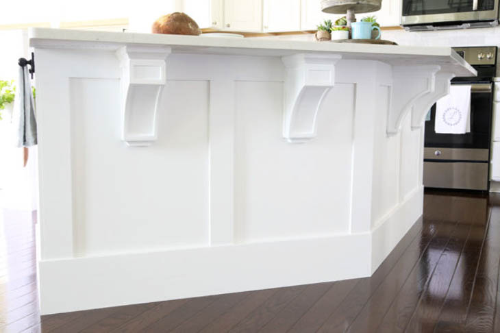 white kitchen island with wood trim and corbels under the countertop