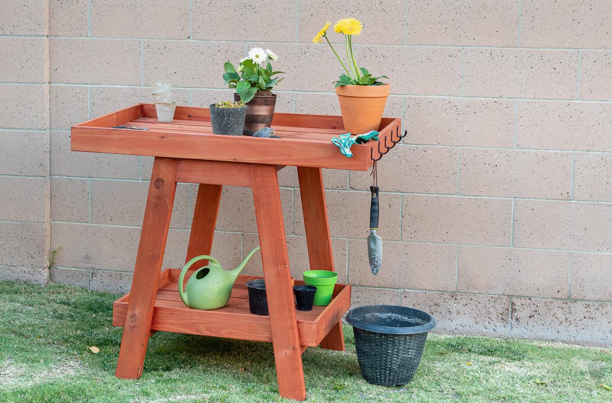 DIY redwood potting bench on grass with pots and plants