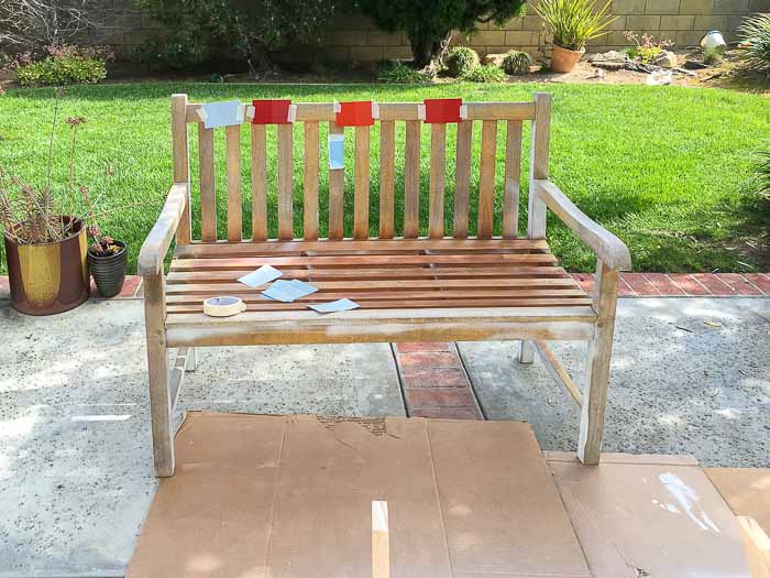 Old outdoor bench with paint chips taped in backyard
