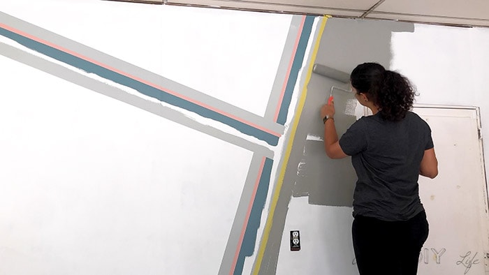 Woman painting dark grap color on the remaining wall