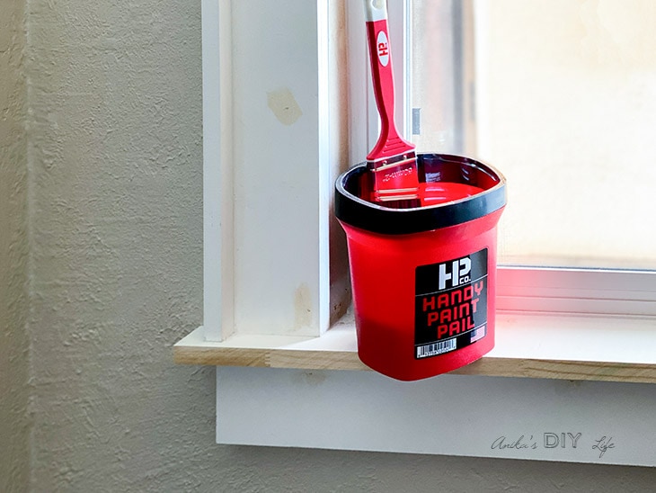 Handy Paint Pail with brush on an unpainted window trim