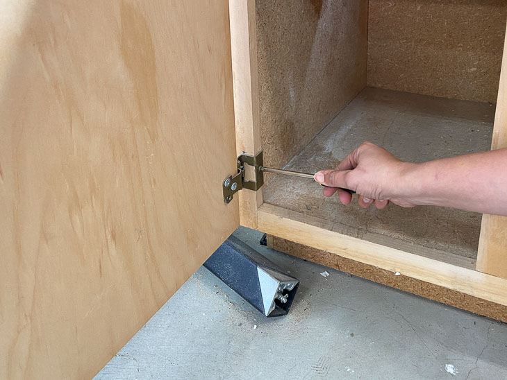 removing cabinet hinge with screw driver before painting the veneer cabinet