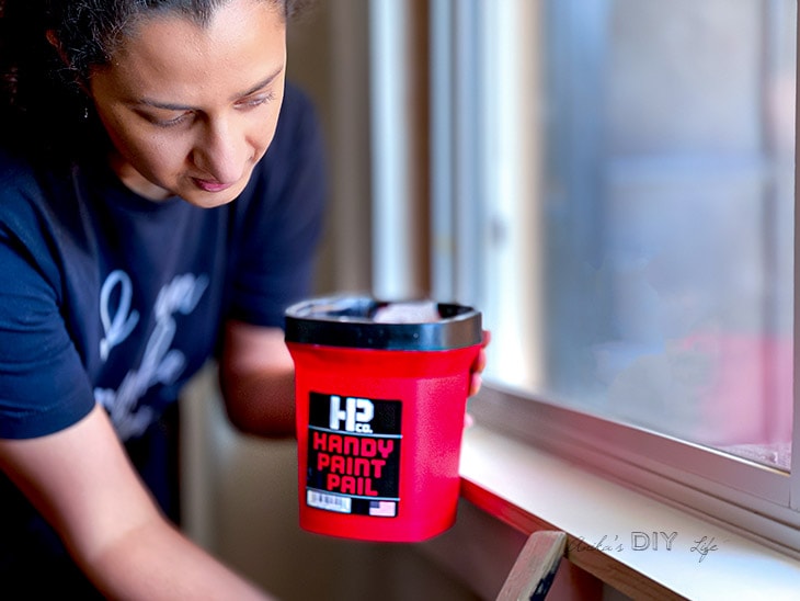 Woman painting trim with handy paint pail