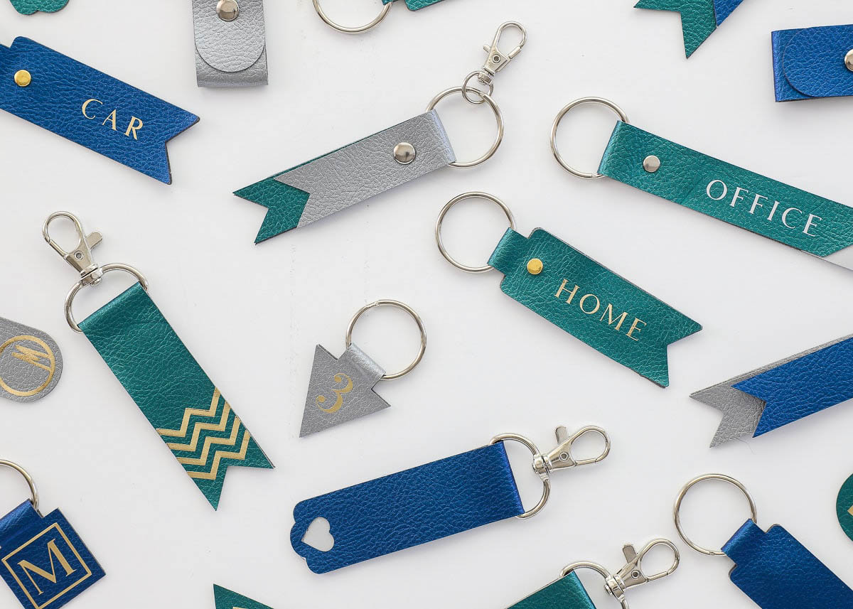 flat lay photo of faux leather keychains in blue and green, different shapes and patterns for gift-giving idea made with Cricut