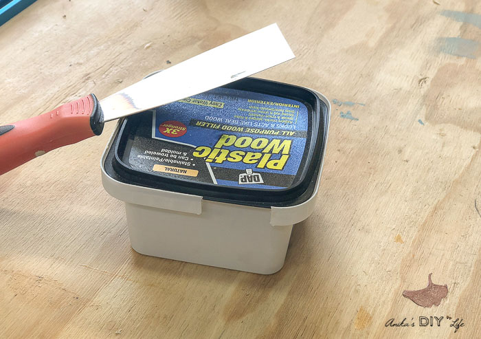 Wood filler and putty knife on worktop